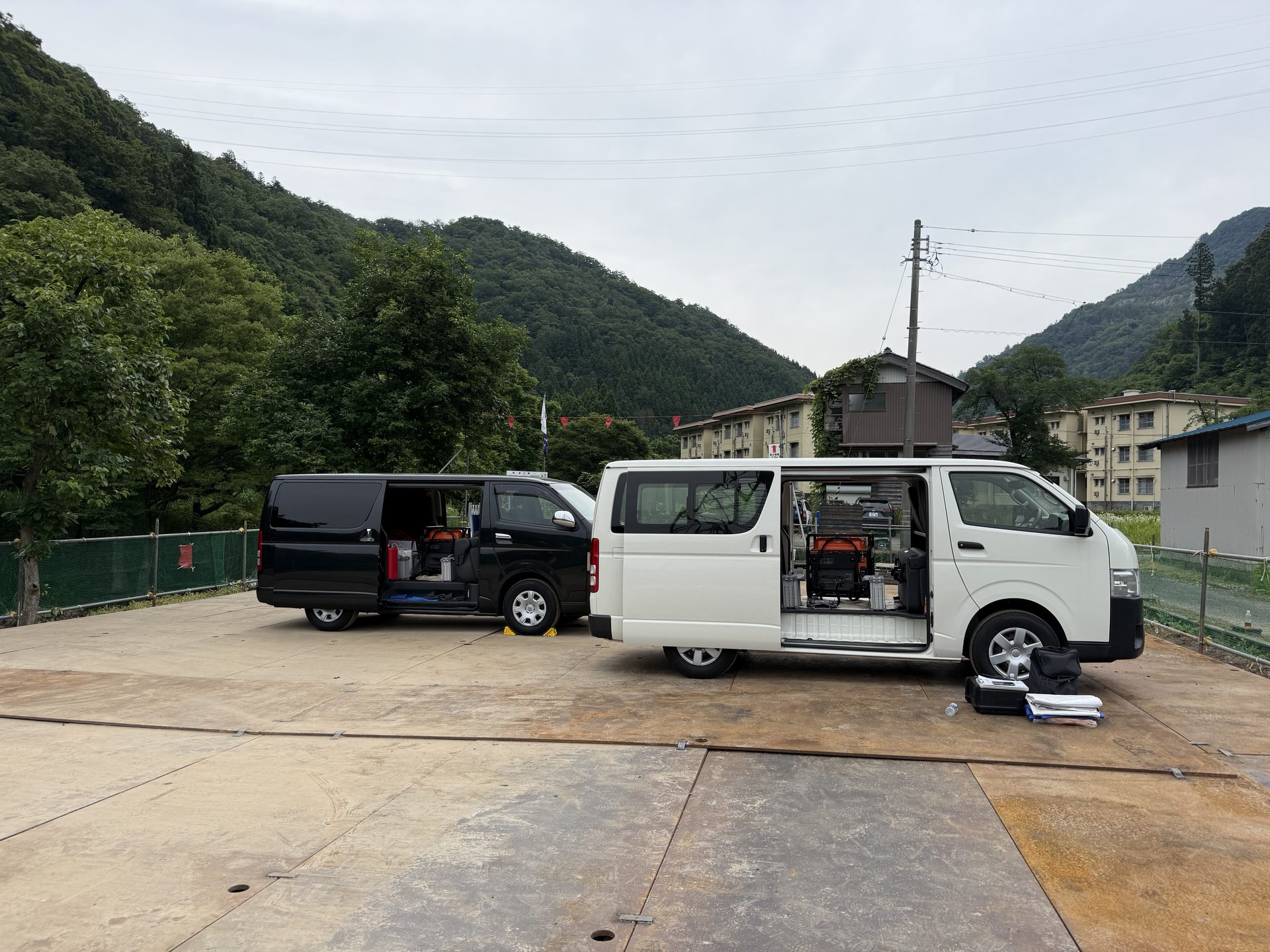 山間部の現場に停車する資機材搭載のハイエース2台